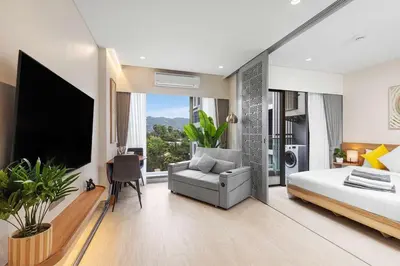 a bedroom with a bed and a couch and a tv at Laguna Lakeside BangTao Phuket in Bang Tao Beach