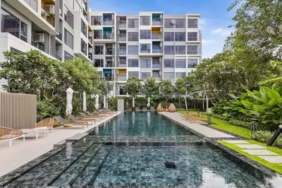 an infinity pool with chairs and a building at Laguna Lakeside BangTao Phuket in Bang Tao Beach