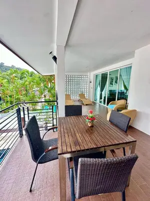 a dining room with a table and chairs on a balcony at The White House Kamala II in Kamala Beach