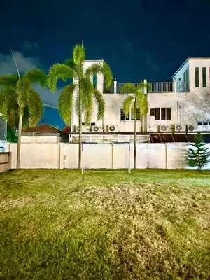 a fence with palm trees in front of a building at The White House Kamala II in Kamala Beach