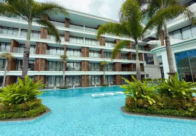 a hotel with a swimming pool and palm trees at Kora Beach Resort Phuket in Bang Tao Beach