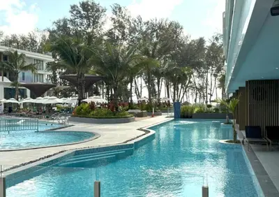 a swimming pool at a resort with palm trees at Kora Beach Resort Phuket in Bang Tao Beach