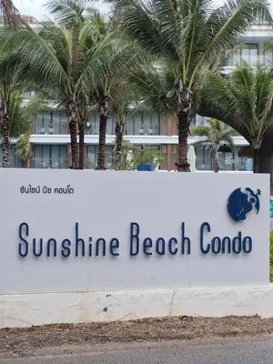 a sign for sunshine beach corona in front of palm trees at Kora Beach Resort Phuket in Bang Tao Beach