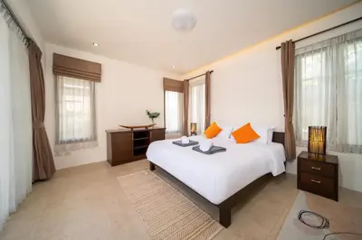 a bedroom with a large white bed with orange pillows at Tropical Pool Villa Thai-modern Villa with an OFFICE in Phuket Town