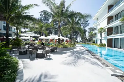 a resort pool with tables and chairs and palm trees at The Sunshine Beach Resort 1-bedroom with a great view in Layan Beach