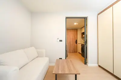 a living room with a white couch and a wooden table at New condo near the sea, Laguna, Choeng Thale 324 in Ban Thalat Choeng Thale