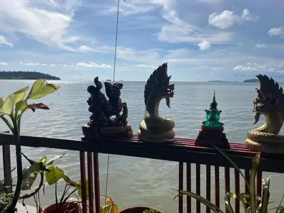 a group of statues sitting on a railing near the water at Fisherman's house on stilts Phuket Old Town in Ban Tha Khreng