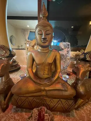 a statue of a buddha sitting on a table at Fisherman's house on stilts Phuket Old Town in Ban Tha Khreng