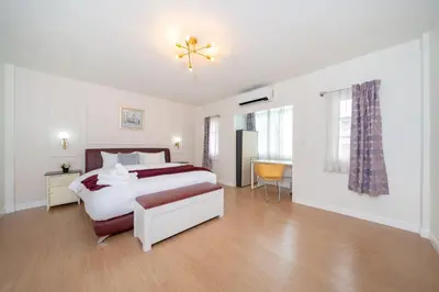 a white bedroom with a bed and a chair in it at 3BR pool at Bangla Patong reach beach in 5m walk in Patong Beach