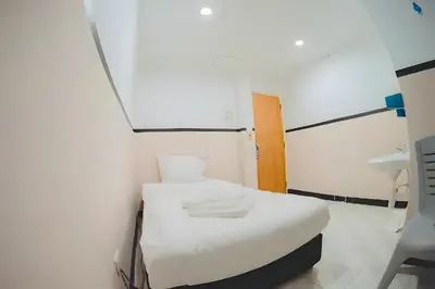 a small room with a white bed and a sink at XX Mitr Inn - ภูเก็ต เมืองเก่า Phuket Old Town 2 in Phuket Town