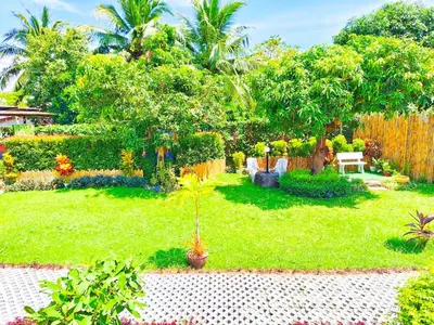a garden with a wooden fence and a green yard at Suki Palm in Ban Bang Chak