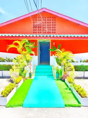 a red house with a blue door and a green lawn at Suki Palm in Ban Bang Chak