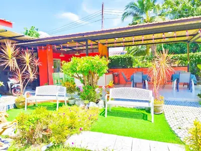 a garden with two white benches and plants at Suki Palm in Ban Bang Chak