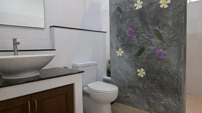 a bathroom with a toilet and a sink with flowers on the shower curtain at Naiharn Beach Holiday Villa 2, Rawai Phuket in Rawai Beach