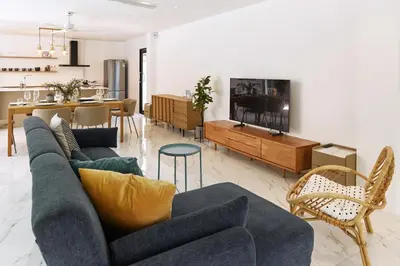 a living room with a blue couch and a kitchen at Modern Villa 4-BR, Breeze - 10 min walk to NaiYang beach in Nai Yang Beach