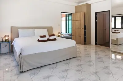 a bedroom with a large white bed and marble floors at Modern Villa 4-BR, Breeze - 10 min walk to NaiYang beach in Nai Yang Beach