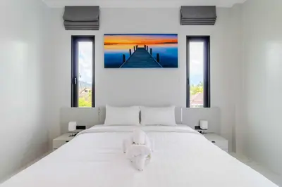 a white bed with a stuffed dog sitting on it at 4BR Big Pool 2 Villas Same Land Near Nai Harn V258 in Rawai Beach
