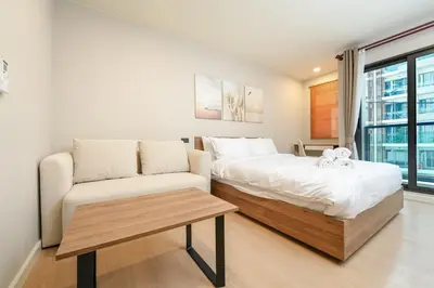 a bedroom with a bed and a couch and a table at Boat Avenue Modern Loft in Ban Thalat Choeng Thale
