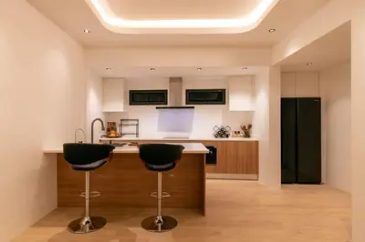 a kitchen with two bar stools and a black refrigerator at Luxury 3 bed villa with private pool, Rawai Phuket in Rawai Beach