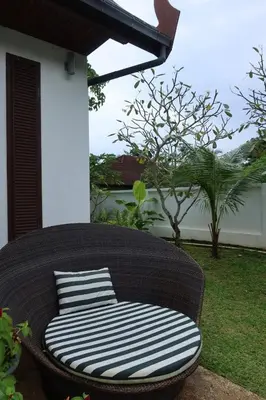 a wicker chair with a striped pillow on a patio at Baan Chang Sanctuary in Laguna Phuket