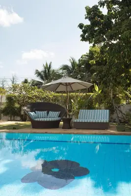 two chairs and an umbrella next to a swimming pool at Baan Chang Sanctuary in Laguna Phuket