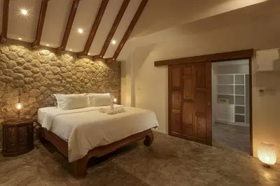 a bedroom with a bed and a stone wall at Baan Chang Sanctuary in Laguna Phuket