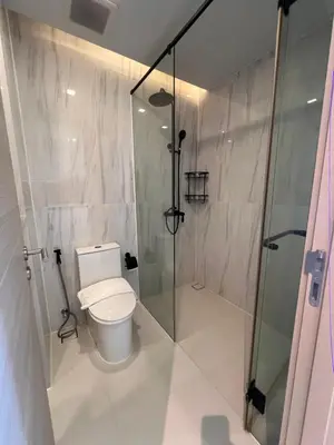 a bathroom with a toilet and a glass shower at Utopia Karon Sea View Apartments in Karon Beach