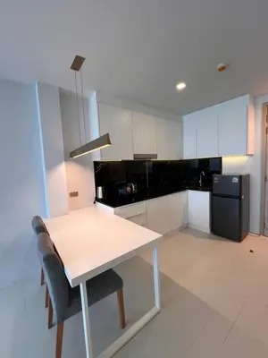 a kitchen with a white table and a black refrigerator at Utopia Karon Sea View Apartments in Karon Beach