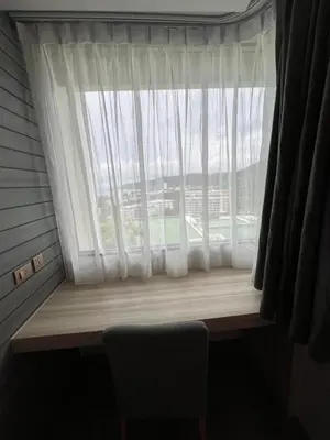 a window with a white curtain and a chair next to it at Utopia Karon Sea View Apartments in Karon Beach