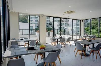 a restaurant with tables and chairs and windows at Utopia Karon Sea View Apartments in Karon Beach