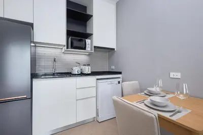 a kitchen with white cabinets and a table with chairs at Title Legendary Bang Tao by My Home Phuket in Ban Nong Chaeng