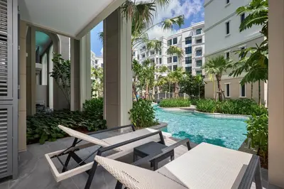 an outdoor patio with chairs and a swimming pool in a building at Title Legendary Bang Tao by My Home Phuket in Ban Nong Chaeng