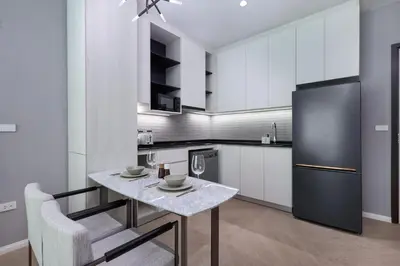 a kitchen with a table and a black refrigerator at Title Legendary Bang Tao by My Home Phuket in Ban Nong Chaeng