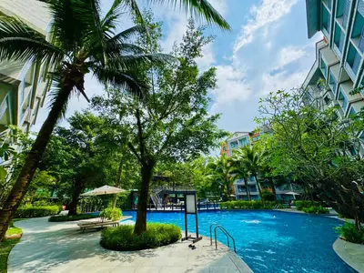 a swimming pool with a palm tree and a building at Cozy studio Pool View near of NaiYang beach in Nai Yang Beach