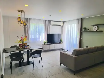 a living room with a couch and a table at Modern 61m² Apt - Central Chalong/ Fast WiFi in Ban Thalat Choeng Thale