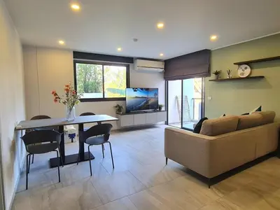 a living room with a couch and a table at Modern 61m² Apt - Central Chalong/ Fast WiFi in Ban Thalat Choeng Thale