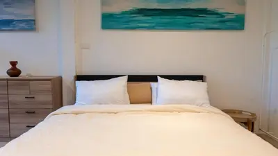 a bedroom with a bed with white sheets and a dresser at The Fifth Bamboo in Laguna Phuket