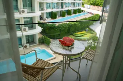 a table with a bowl of watermelon on a balcony at Cozy 1Bdr Apartment in La Vita Rawai Nai Harn in Rawai Beach