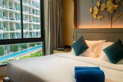 a bed in a hotel room with a large window at Cozy 1Bdr Apartment in La Vita Rawai Nai Harn in Rawai Beach