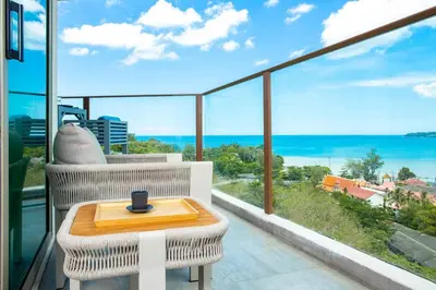 a balcony with a table and a view of the ocean at Modern condo with full sea view, 4 min walk to Kamala beach in Kamala Beach
