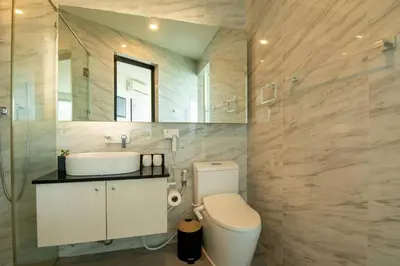 a bathroom with a toilet and a sink and a mirror at Modern condo with full sea view, 4 min walk to Kamala beach in Kamala Beach