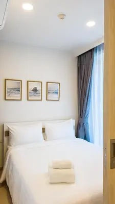 a bedroom with a white bed with a window at Стильные апартаменты с террасой in Laguna Phuket