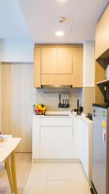 a kitchen with white counters and wooden cabinets at Стильные апартаменты с террасой in Laguna Phuket