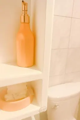 a bottle of orange liquid sitting on a shelf next to a toilet at Nova Patong in Patong Beach