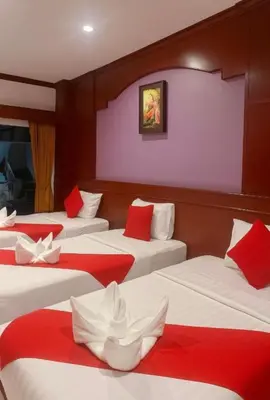 a room with four beds with red and white sheets at Nova Patong in Patong Beach