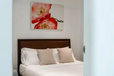 a bedroom with a bed with white sheets and red flowers at Kata Beach Tropical Hillside Retreat Jungle View in Kata Beach