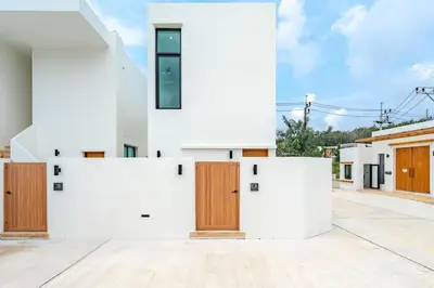 a house with white walls and wooden doors at Tropical Holiday Retreat 1BR Villa Near Bangtao in Ban Pak Lak