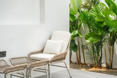 a rattan chair with a pillow sits next to two chairs at Tropical Holiday Retreat 1BR Villa Near Bangtao in Ban Pak Lak