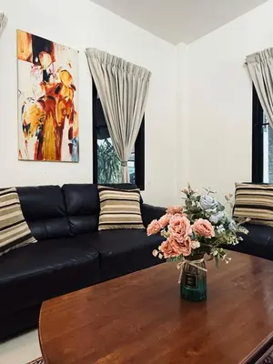 a living room with a black couch and a vase with flowers at Cozy family cottage w pool Bang Tao in Phuket