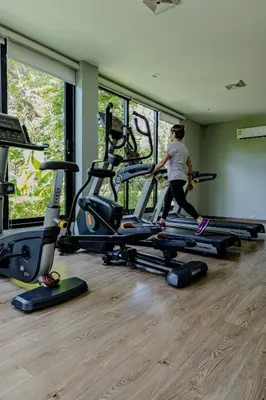 a woman running on a treadmill in a gym at Comfy studio - 10 min walk to NaiYang Beach in Nai Yang Beach